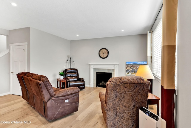 living room with recessed lighting, baseboards, light wood-style flooring, and a fireplace