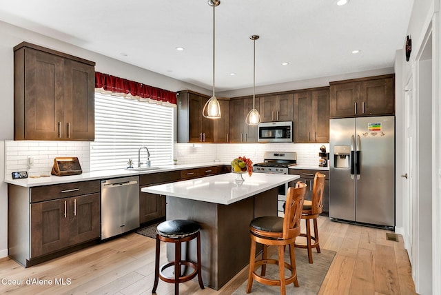 kitchen with dark brown cabinets, appliances with stainless steel finishes, a kitchen breakfast bar, and a sink