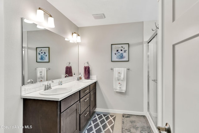 bathroom featuring double vanity, a shower stall, baseboards, and a sink