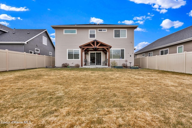 rear view of house with a gazebo, a yard, and a fenced backyard