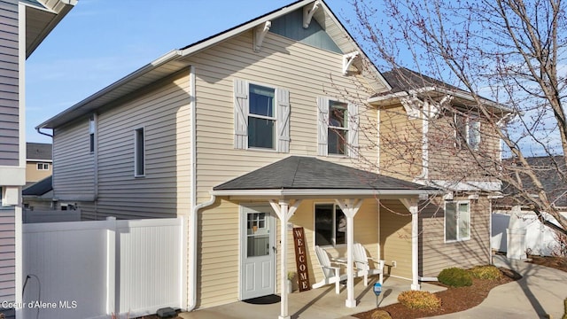 back of property featuring a porch, a shingled roof, and fence