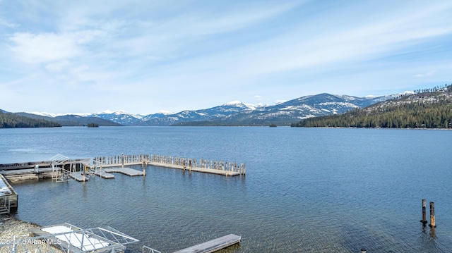 property view of water with a mountain view and a dock