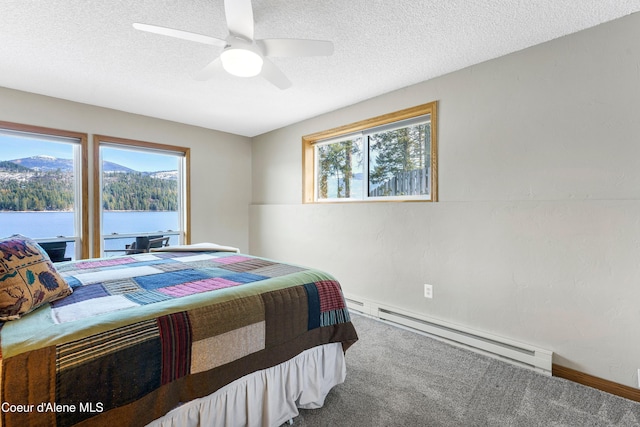 carpeted bedroom with multiple windows, a textured ceiling, a water view, and a baseboard radiator