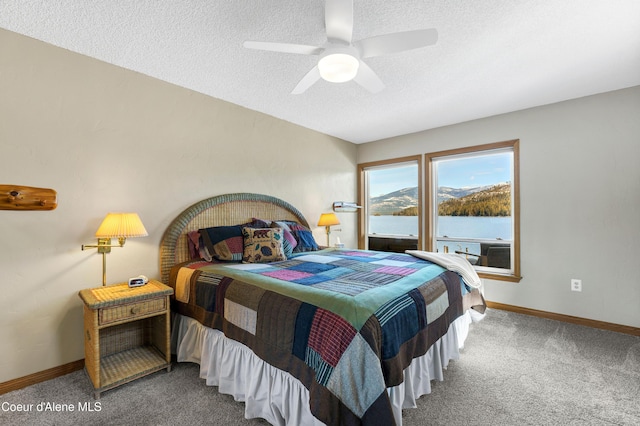 carpeted bedroom featuring baseboards, a water view, and a textured ceiling