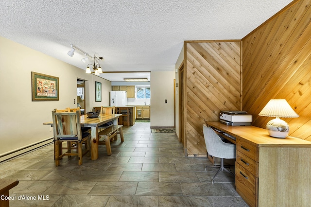 dining room with a textured ceiling, baseboard heating, wood walls, and built in desk