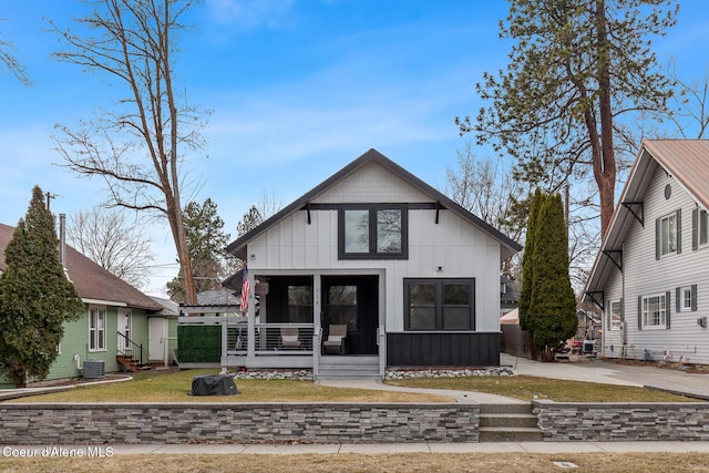 view of front of property with a porch, entry steps, a front lawn, central air condition unit, and board and batten siding