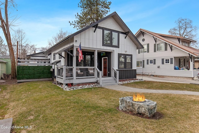 view of front facade featuring a fire pit, board and batten siding, and a front yard