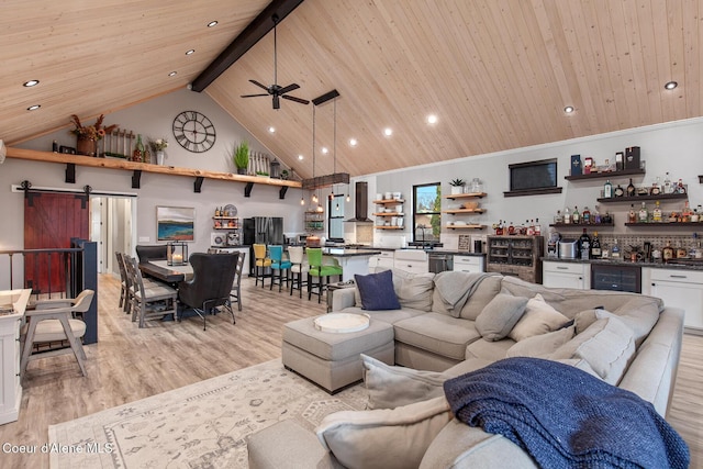 living room with high vaulted ceiling, a barn door, a bar, wooden ceiling, and light wood finished floors