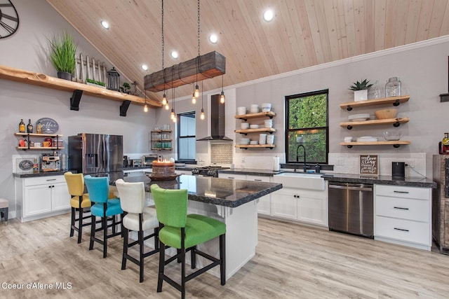 kitchen with open shelves, wall chimney range hood, wood ceiling, appliances with stainless steel finishes, and a sink