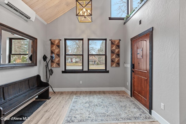 entrance foyer featuring plenty of natural light, a wall mounted air conditioner, baseboards, and wood finished floors