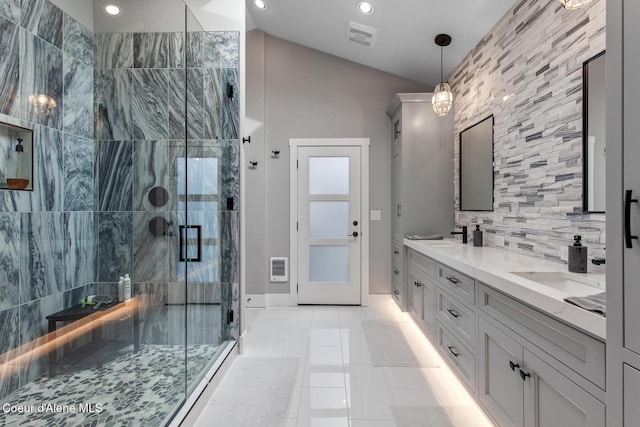 full bathroom with a sink, backsplash, a shower stall, double vanity, and vaulted ceiling