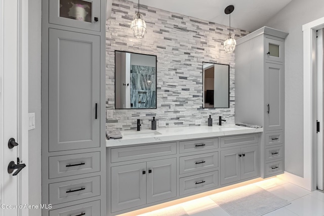 bathroom featuring double vanity, decorative backsplash, tile patterned floors, and a sink