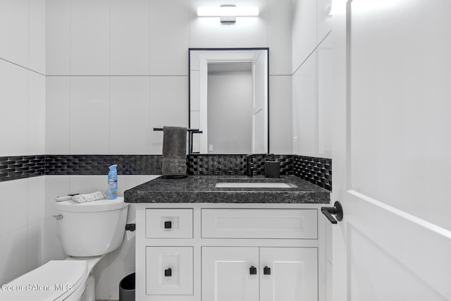 bathroom with tasteful backsplash, tile walls, vanity, and toilet