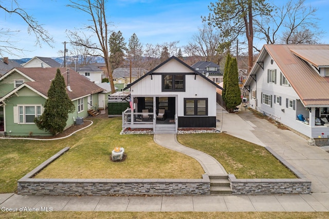 back of house with a yard, covered porch, a residential view, and driveway