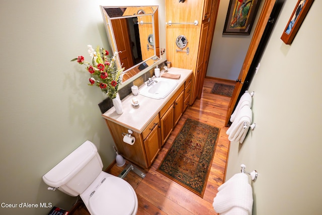 bathroom with baseboards, toilet, hardwood / wood-style floors, and vanity