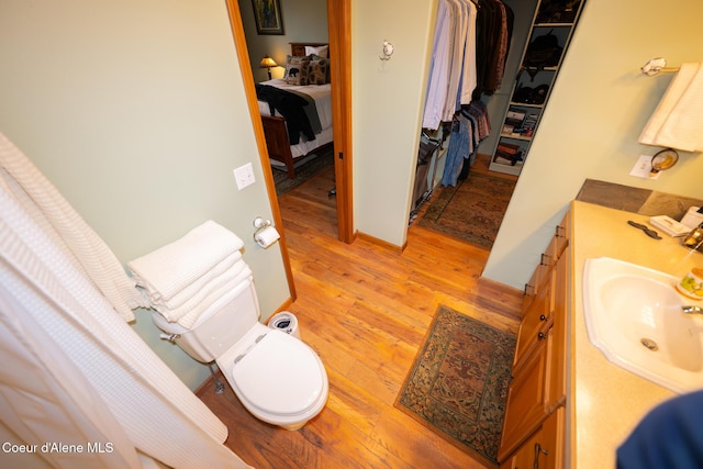 ensuite bathroom featuring connected bathroom, toilet, wood finished floors, and vanity