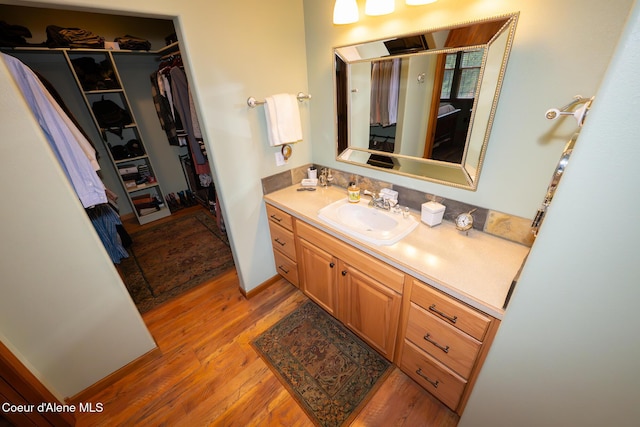 bathroom with vanity, a walk in closet, and wood finished floors