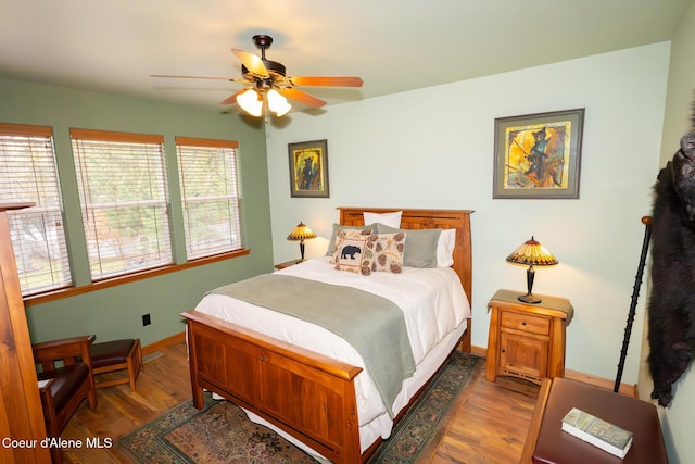 bedroom with a ceiling fan, baseboards, and wood finished floors