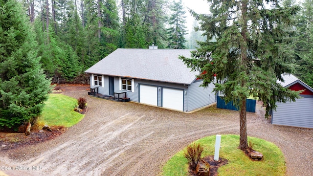 ranch-style home featuring a shingled roof, an attached garage, driveway, and a chimney