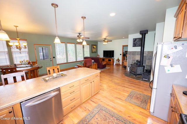 kitchen featuring ceiling fan, dishwasher, light wood-type flooring, freestanding refrigerator, and a wood stove