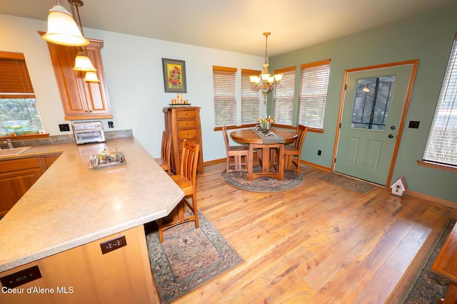 dining area featuring baseboards, light wood-type flooring, and a chandelier