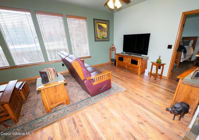 living area with baseboards, a ceiling fan, and wood finished floors