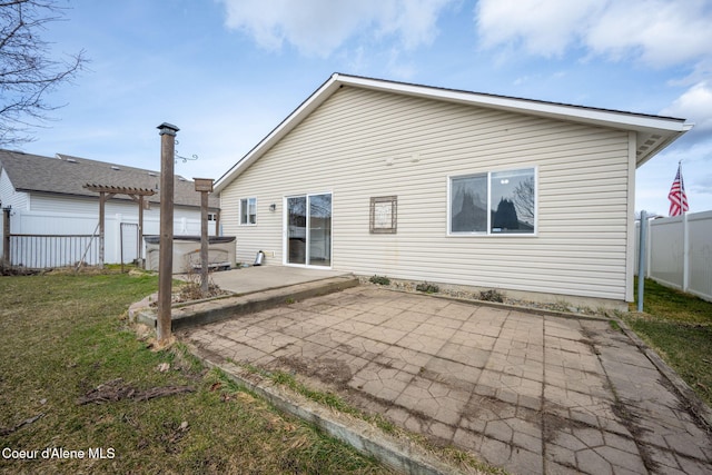 back of house with a hot tub, fence, a lawn, a pergola, and a patio