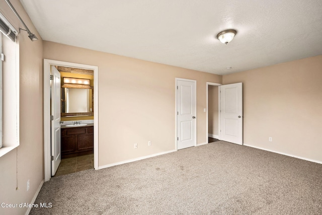 unfurnished bedroom featuring a sink, baseboards, ensuite bath, and carpet flooring