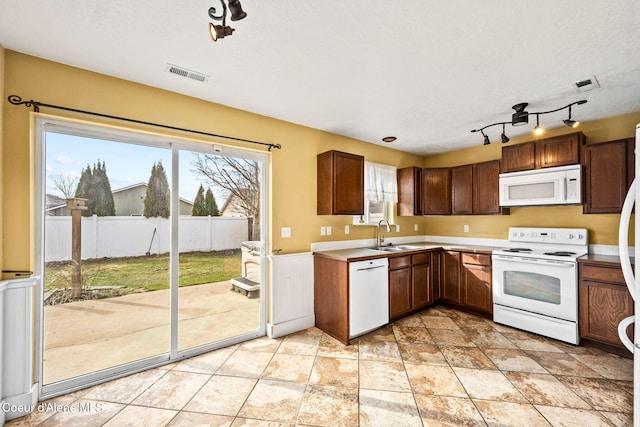 kitchen with visible vents, light countertops, white appliances, a textured ceiling, and a sink