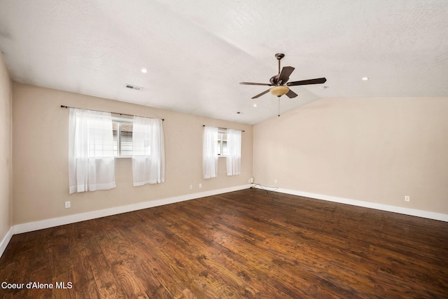 spare room featuring a ceiling fan, wood finished floors, baseboards, visible vents, and vaulted ceiling