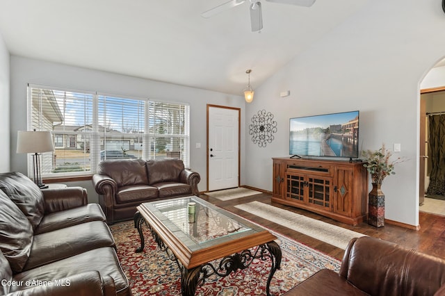 living room featuring baseboards, ceiling fan, vaulted ceiling, wood finished floors, and arched walkways