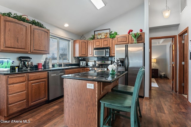 kitchen with visible vents, a kitchen island, appliances with stainless steel finishes, dark wood-style floors, and a sink