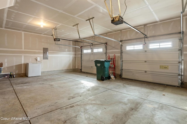 garage featuring electric panel, a garage door opener, and fridge