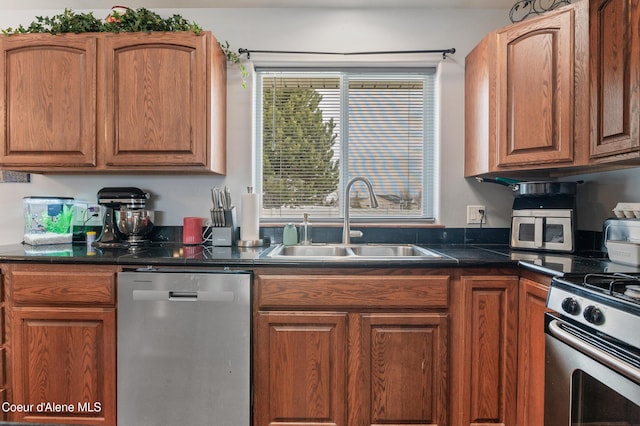 kitchen featuring dark countertops, appliances with stainless steel finishes, brown cabinetry, and a sink