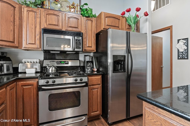 kitchen featuring dark wood-type flooring, visible vents, appliances with stainless steel finishes, and brown cabinets