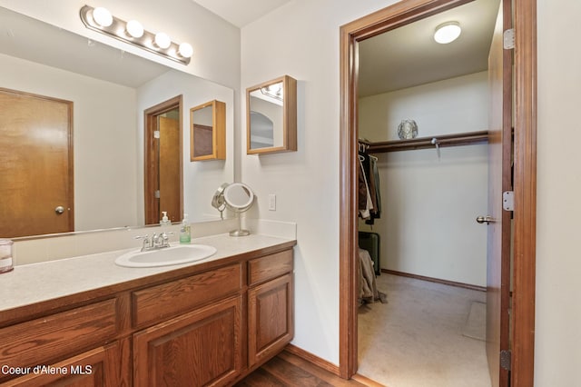 bathroom featuring vanity, a walk in closet, and baseboards