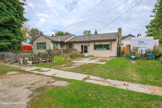 single story home with a chimney, a front lawn, and fence