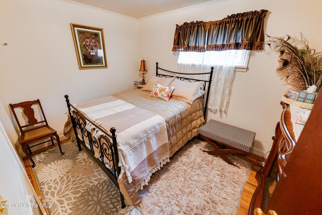 bedroom with crown molding, baseboards, and wood finished floors