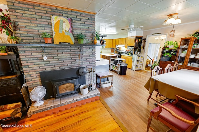 living area with light wood-style flooring, ceiling fan, and ornamental molding