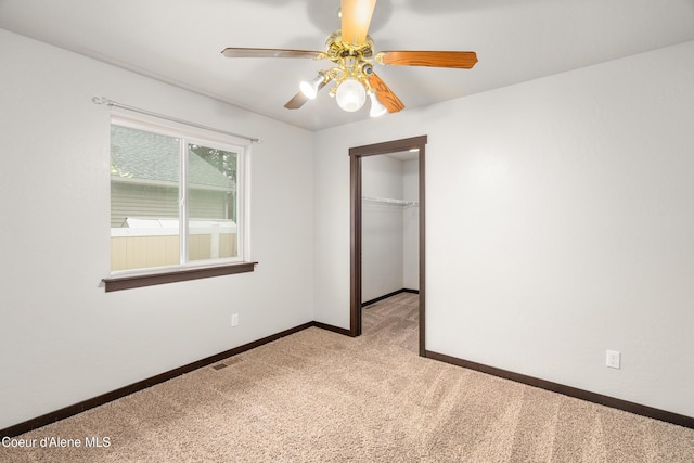 unfurnished bedroom with visible vents, a walk in closet, baseboards, carpet, and a closet