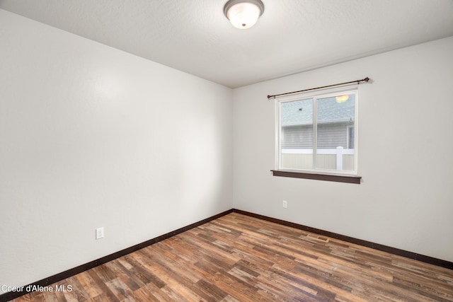 unfurnished room with visible vents, wood finished floors, baseboards, and a textured ceiling