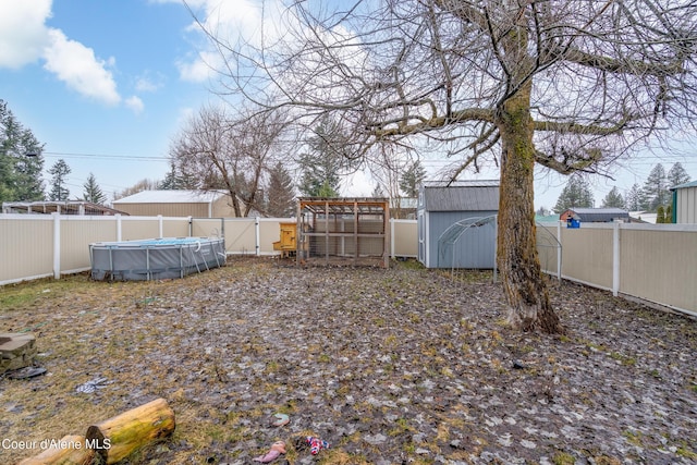 view of yard featuring an outbuilding, a storage unit, a fenced backyard, and a fenced in pool