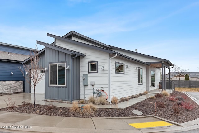 exterior space with board and batten siding, driveway, and fence