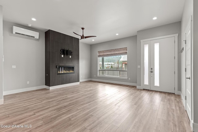 unfurnished living room featuring recessed lighting, a fireplace, a wall mounted air conditioner, and light wood-style floors