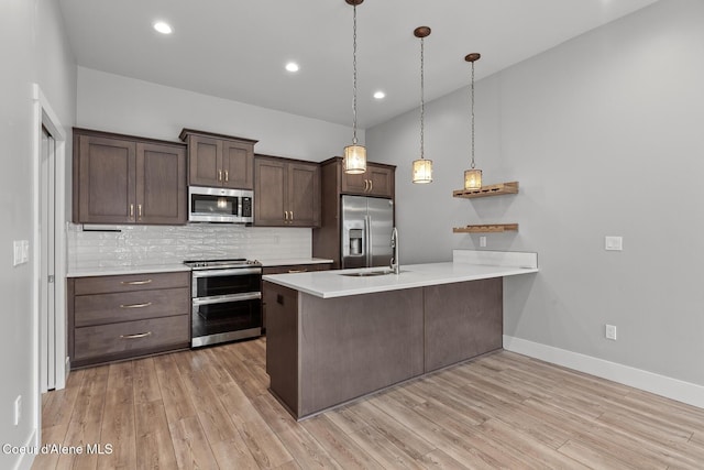 kitchen with light wood finished floors, a peninsula, stainless steel appliances, light countertops, and dark brown cabinets