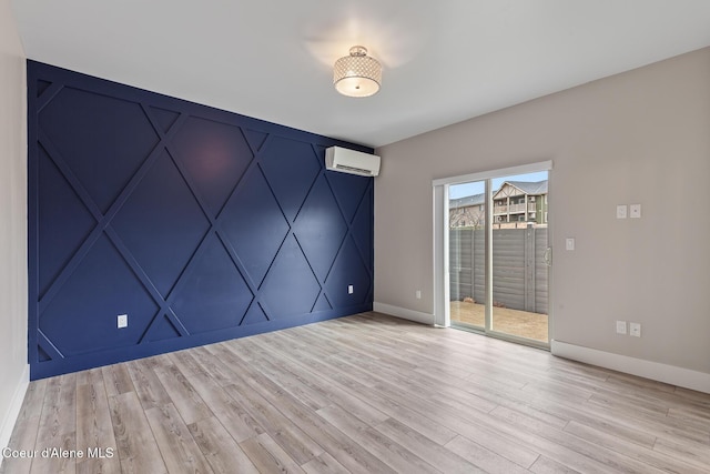 empty room with light wood finished floors, baseboards, and a wall mounted air conditioner