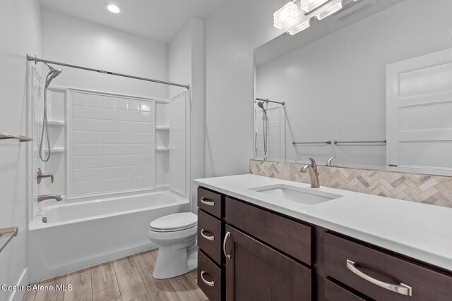 full bath featuring toilet, backsplash, wood finished floors, bathtub / shower combination, and vanity