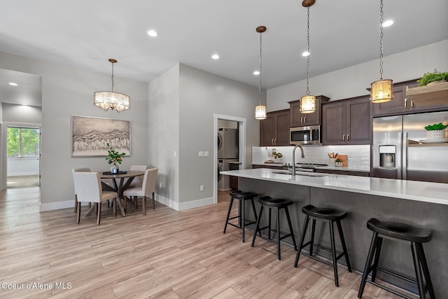 3016 N Casa Ct, Coeur Dalene, ID 83814 - kitchen with stainless steel appliances, light countertops, stacked washer / drying machine, a kitchen breakfast bar, and dark brown cabinets