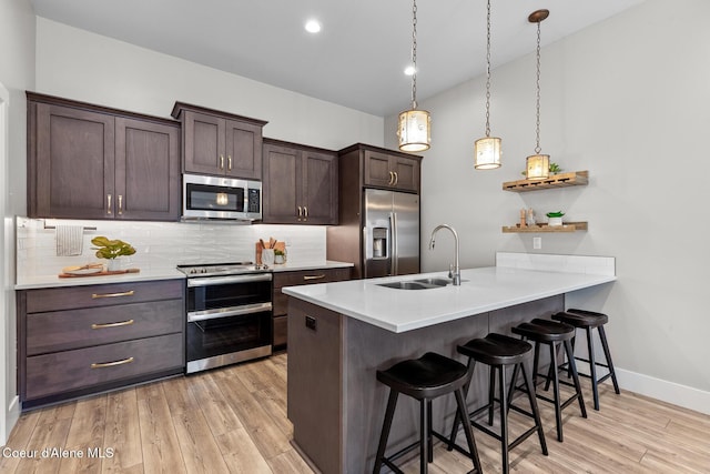 3016 N Casa Ct, Coeur Dalene, ID 83814 - kitchen featuring appliances with stainless steel finishes, a kitchen bar, tasteful backsplash, dark brown cabinets, and a peninsula