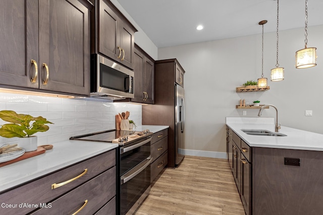 3016 N Casa Ct, Coeur Dalene, ID 83814 - kitchen featuring appliances with stainless steel finishes, dark brown cabinetry, light wood-style flooring, a peninsula, and backsplash